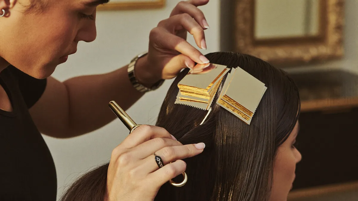 Close-up of a stylist's hands placing foils — the kind of precise, in-person work that resists automation